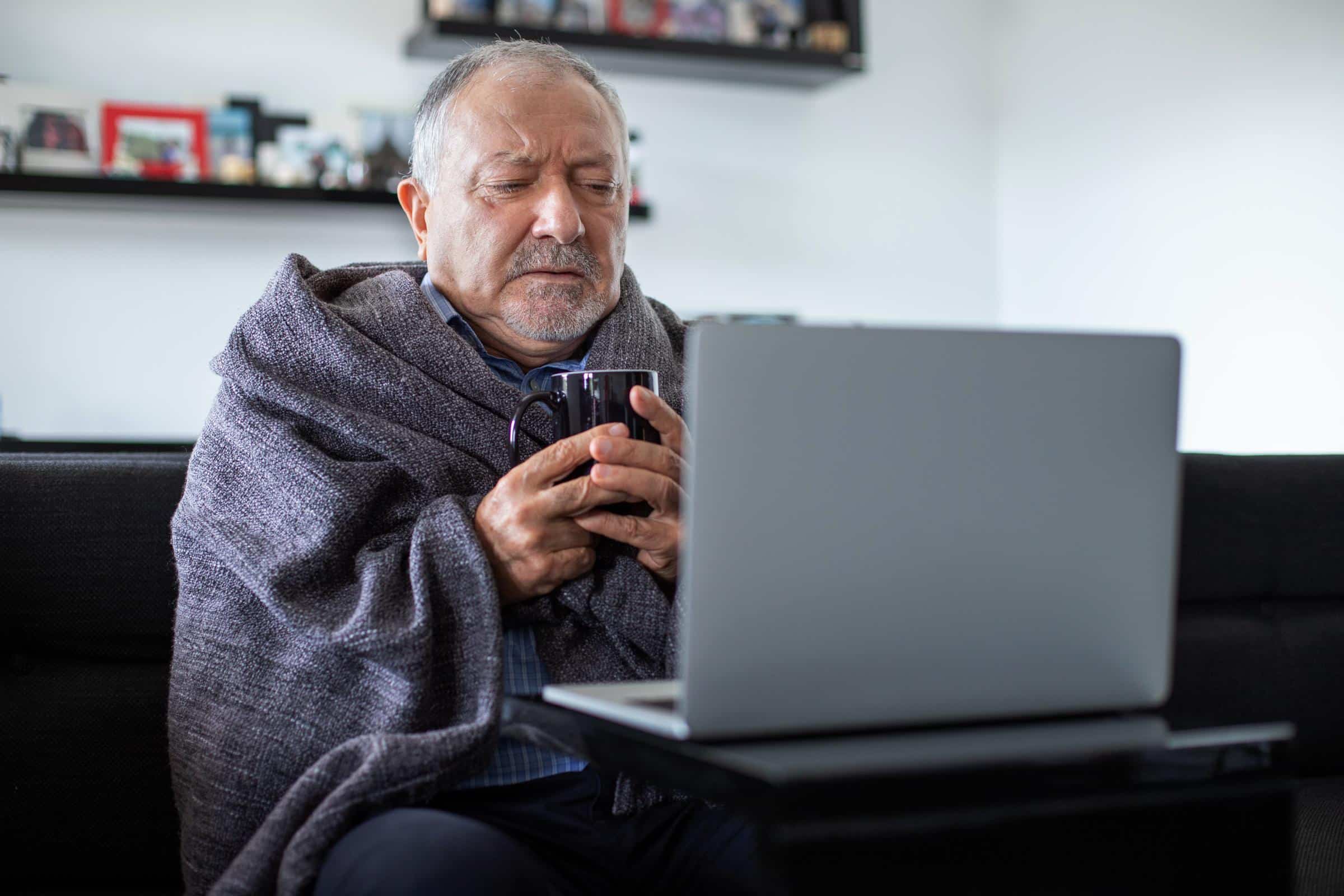 Man wrapped in blanket with laptop