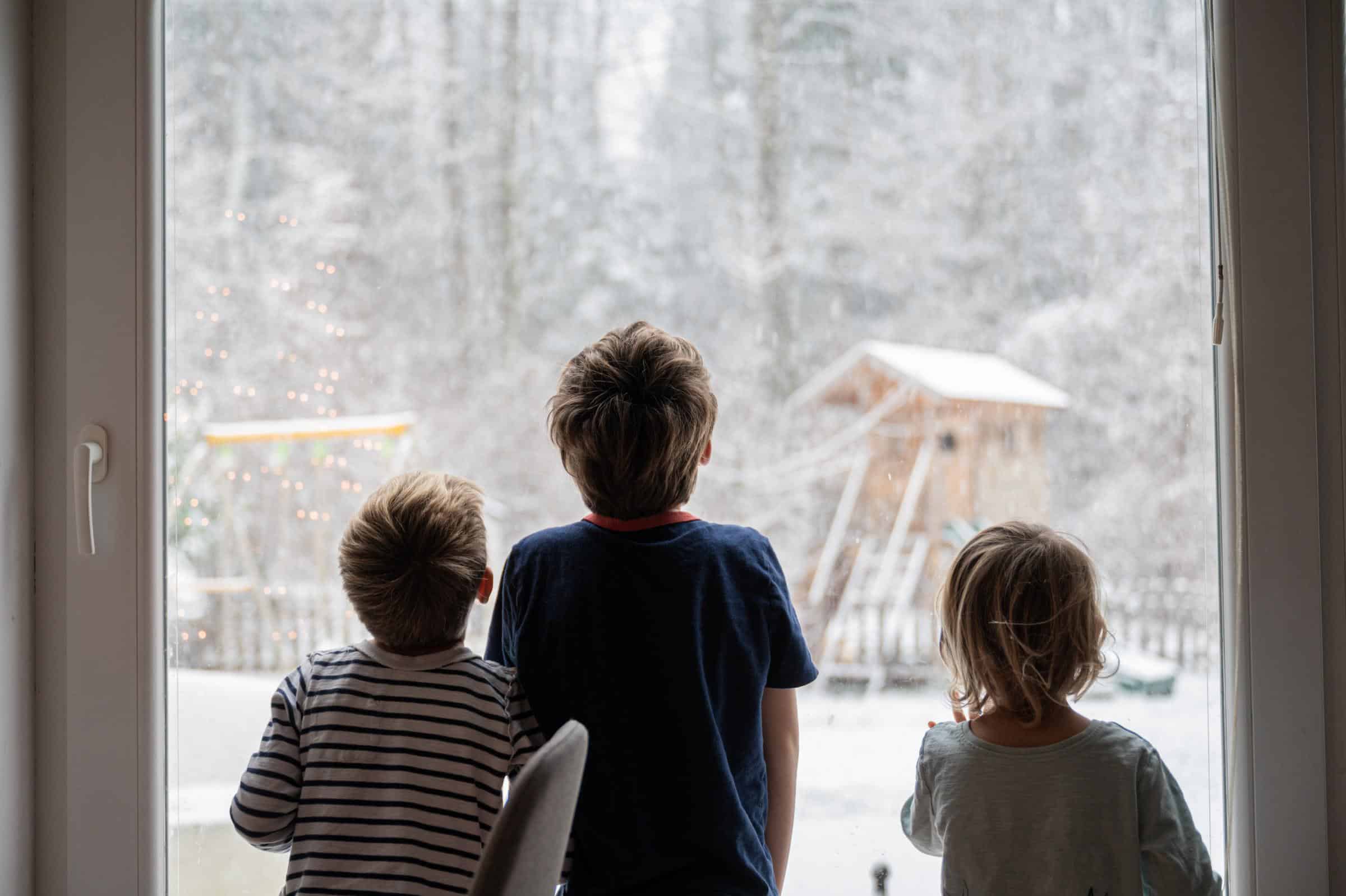 Children looking out window in winter
