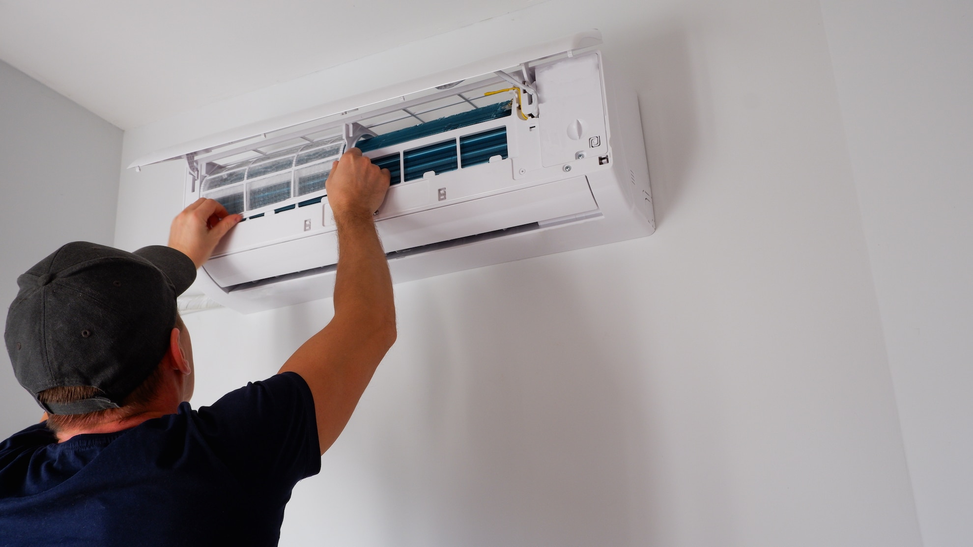 man performing maintenance to heat pump ahead of spring