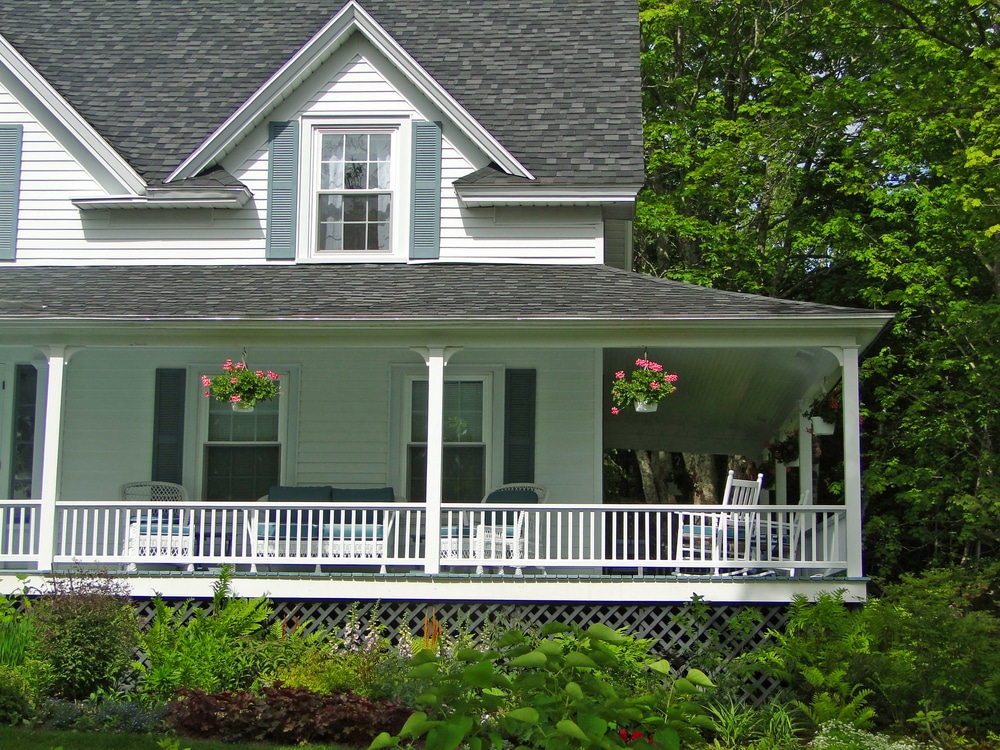 Exterior view of a large cape-style house with a beautiful wrap-around porch.