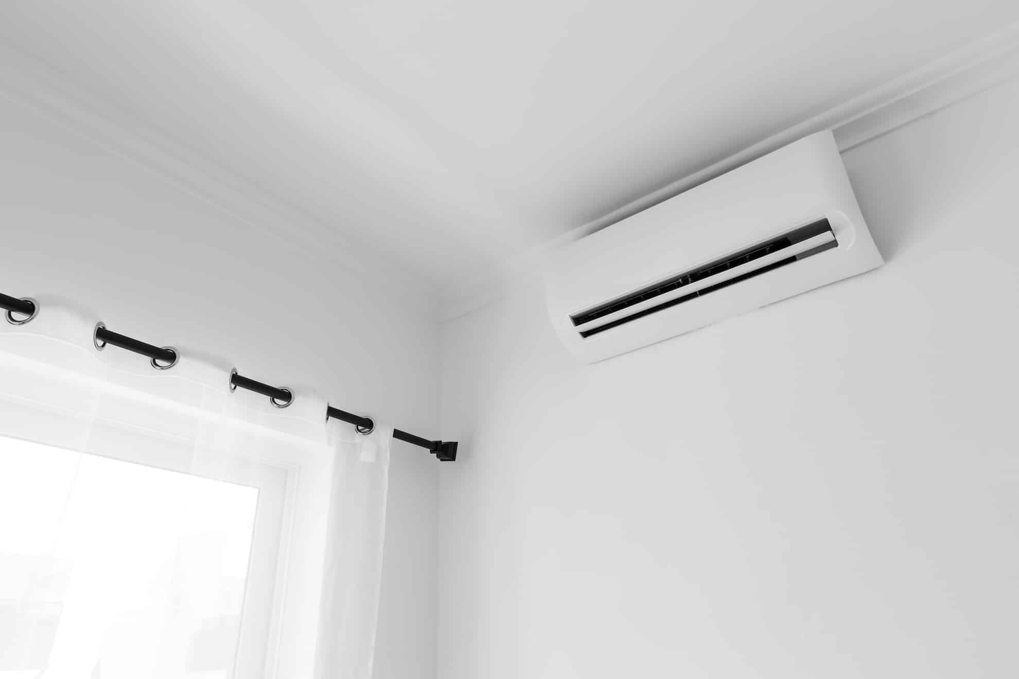 Flat air conditioner on white wall in room interior